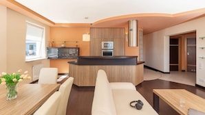 A modern kitchen with a central island, a dining area with a table and chairs, and a living area with a sofa.