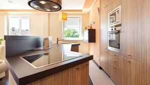 A modern kitchen with a central island, built-in oven, and a skylight.