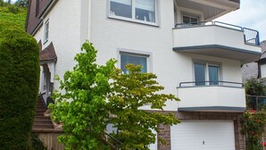 Une maison à deux étages avec un garage, un mur de soutènement en pierre et une pelouse bien entretenue.
