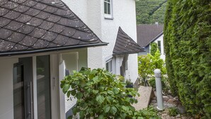 Un bâtiment avec un toit recouvert de tuiles, une porte en verre et un chemin de pierre menant à un portail.