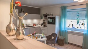Une cuisine moderne avec un coin repas, comprenant des vases en acier inoxydable, une table à manger et une fenêtre avec des rideaux.