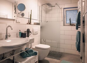 A modern bathroom with a sink, toilet, and shower. - Relaxing, modern apartment in a sunny location (Klotten)