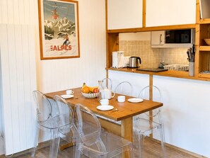 A dining area with a wooden table, clear chairs, and a poster on the wall.