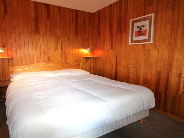 A wooden-paneled room with a bed, a nightstand, and a wall-mounted lamp. - Champagny-en-Vanoise, Apartment 6 ppl, 35 sqm, 2 Rooms (Champagny-en-Vanoise)