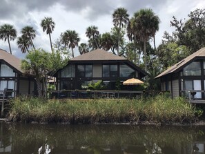 A two-story building with a flat roof, large windows, and a thatched umbrella.