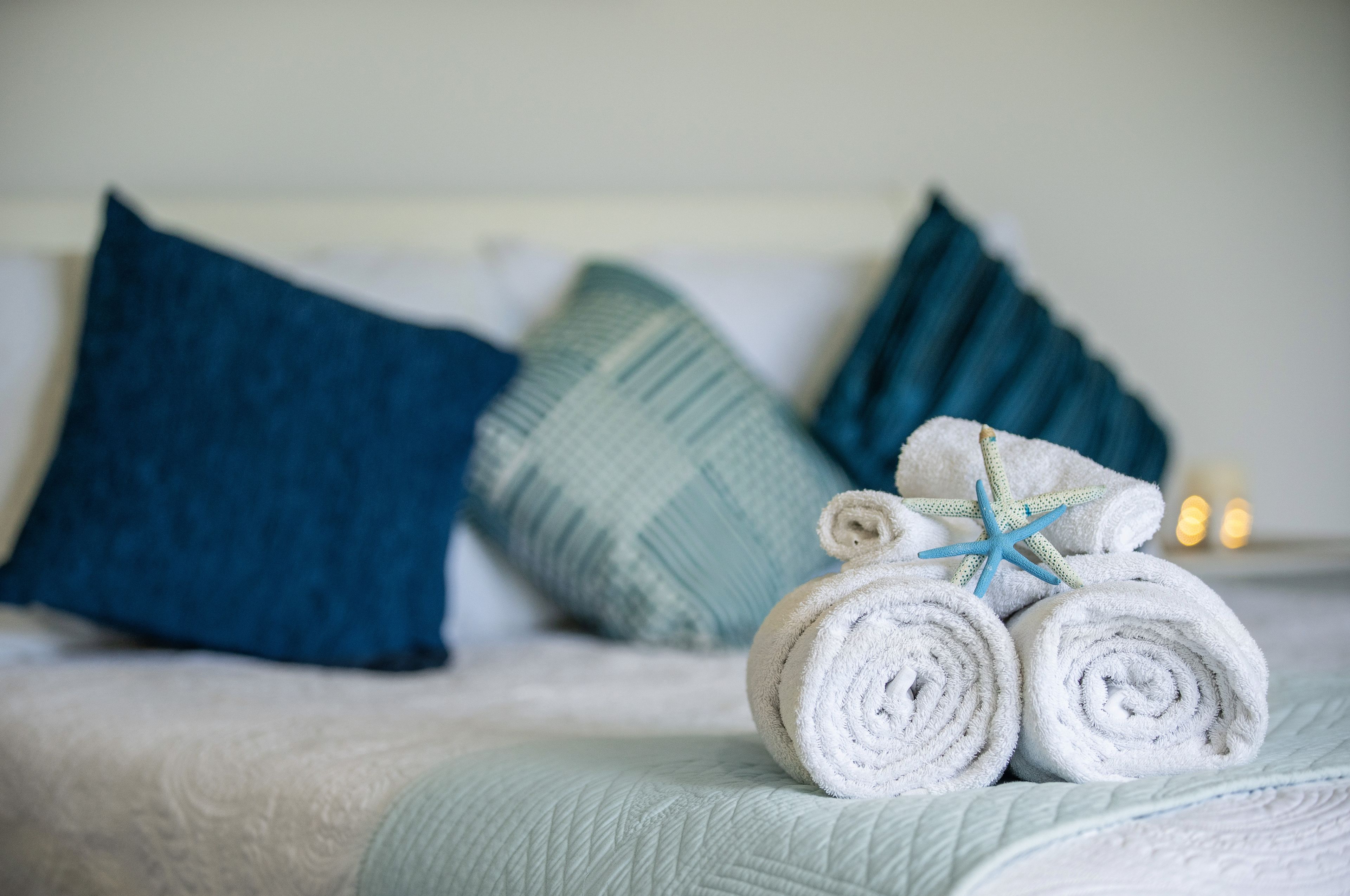 Un lit avec des serviettes blanches roulées et une étoile de mer bleue en guise de décoration.