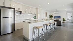 Une cuisine moderne équipée d’un réfrigérateur en acier inoxydable, d’un four à micro-ondes et d’un grand îlot central avec des tabourets de bar.