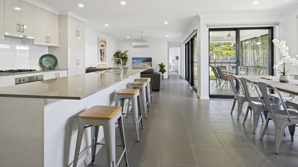 Une cuisine moderne dotée d’un îlot central, de tabourets de bar et d’un coin repas avec des chaises et une table.