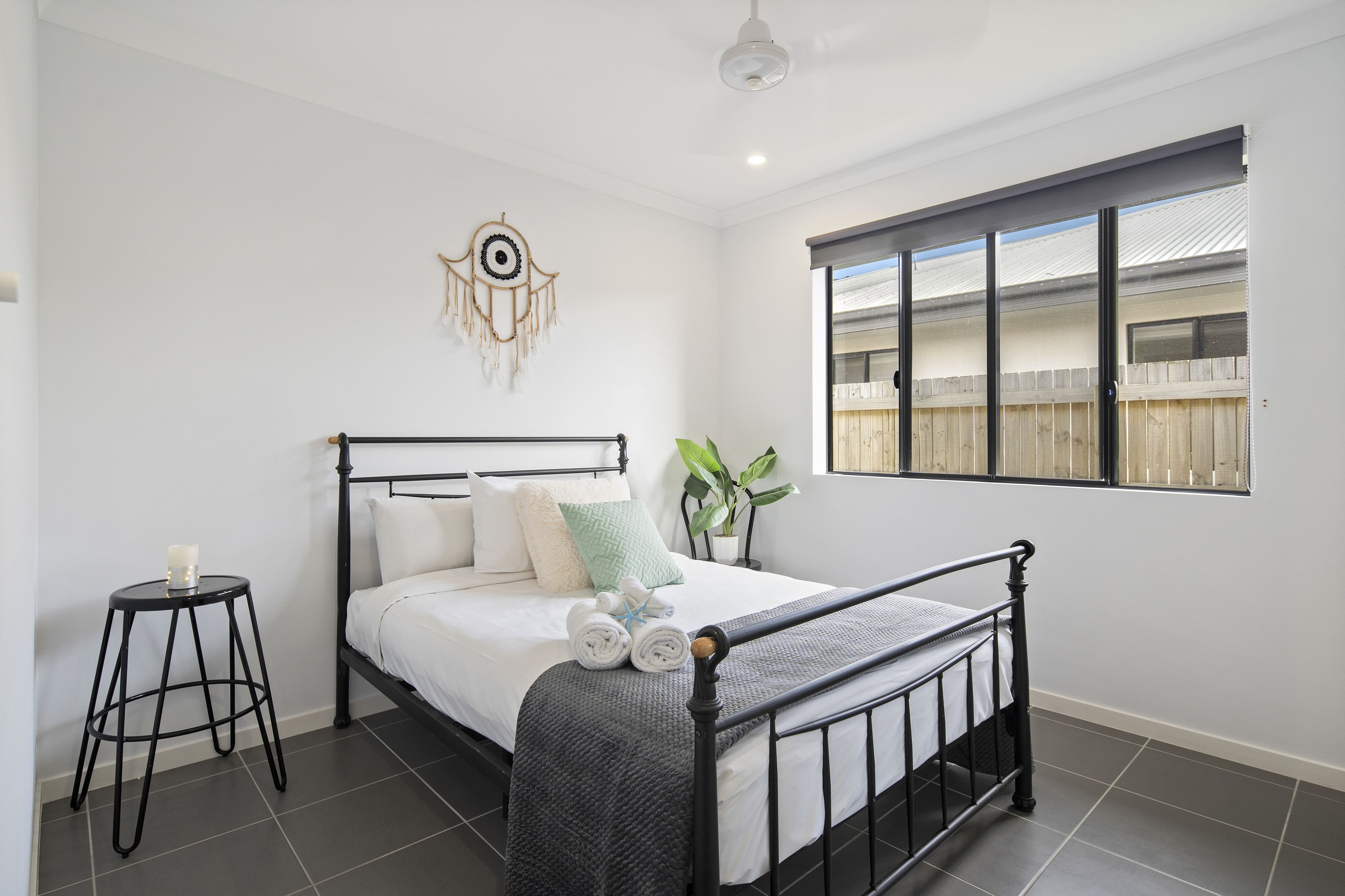 A neatly made bed with a headboard, a bedside table with a candle, and a wall decoration.