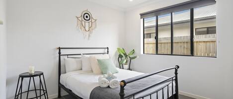 A neatly made bed with a headboard, a bedside table with a candle, and a wall decoration.