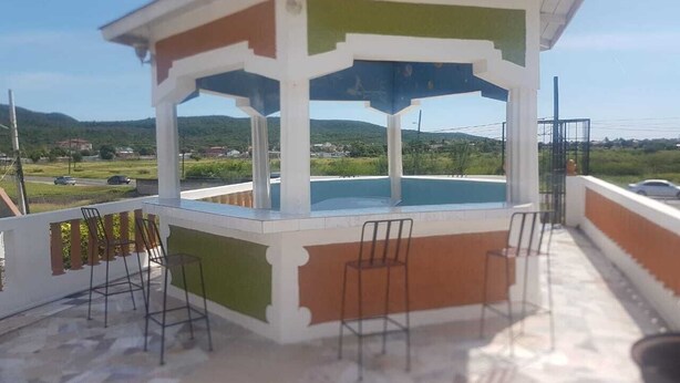 A gazebo with a tiled roof overlooking a swimming pool. - Victoria's Place (Portmore)
