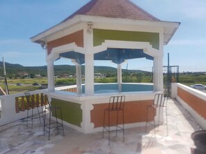 A gazebo with a tiled roof overlooking a swimming pool. - Victoria's Place (Portmore)