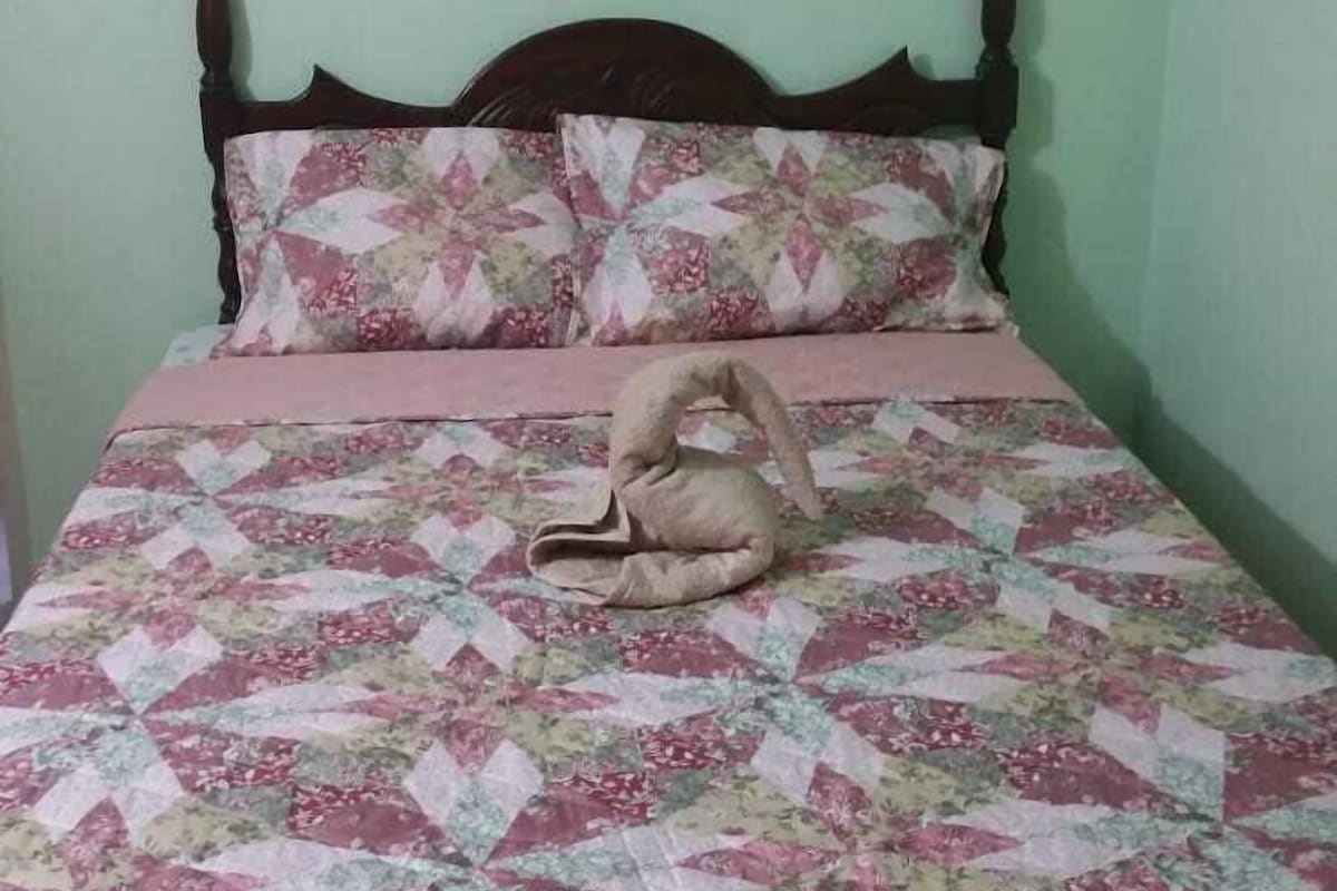 A bed with a floral quilt, a wooden headboard, and a pillow with a similar pattern.