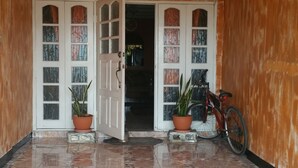 A spacious room with a tiled floor, a ceiling fan, and a bicycle leaning against the wall. - Victoria's Place (Portmore)