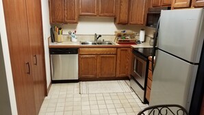 A compact kitchen with wooden cabinets, a stainless steel refrigerator, and a dishwasher. - Scenic Setting Just 8 Minutes From Athens (Athens)