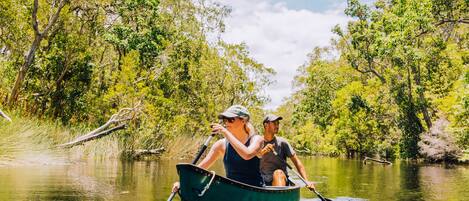A narrow waterway with a green boat carrying two people.