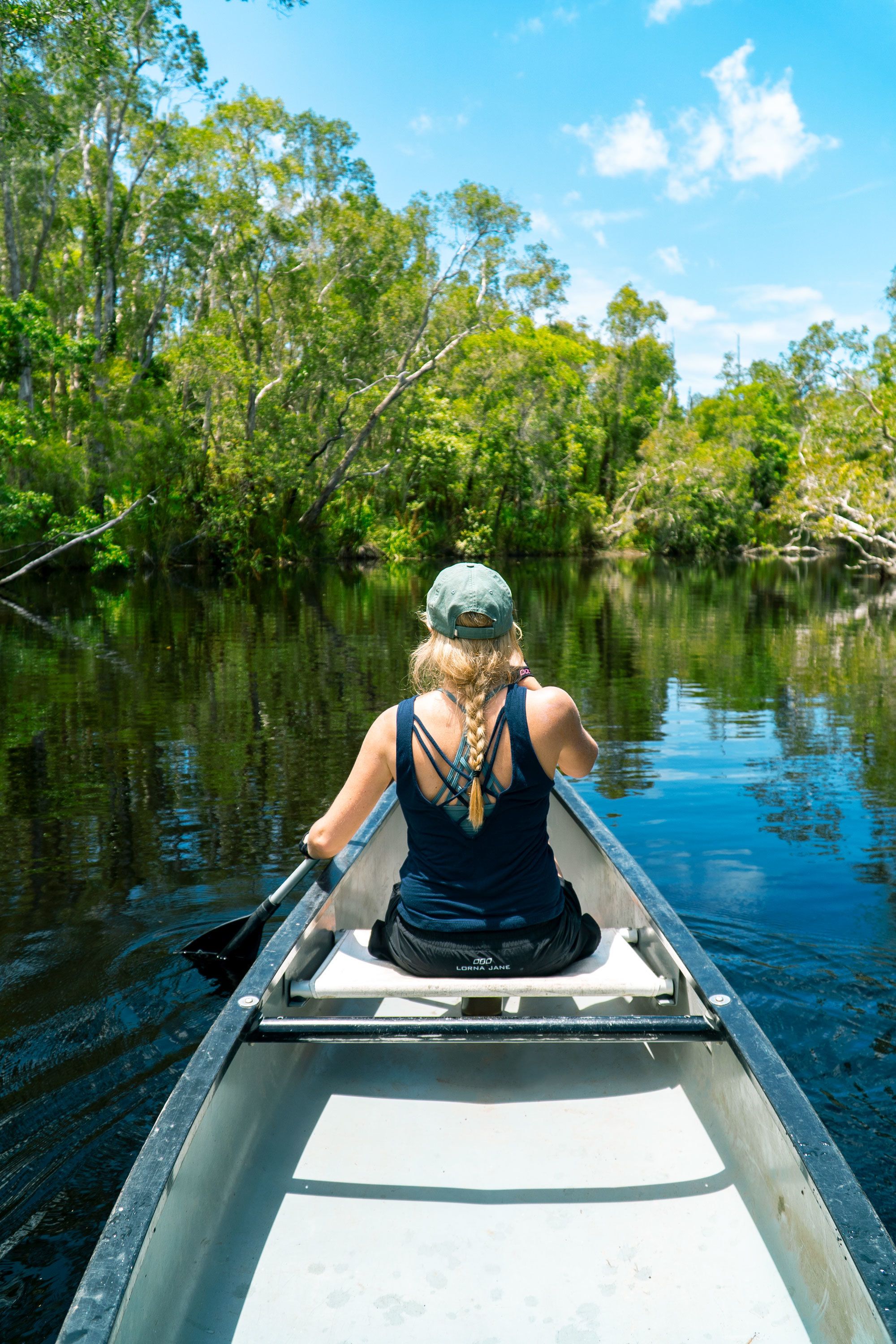 A person in a canoe on a calm river surrounded by dense greenery.