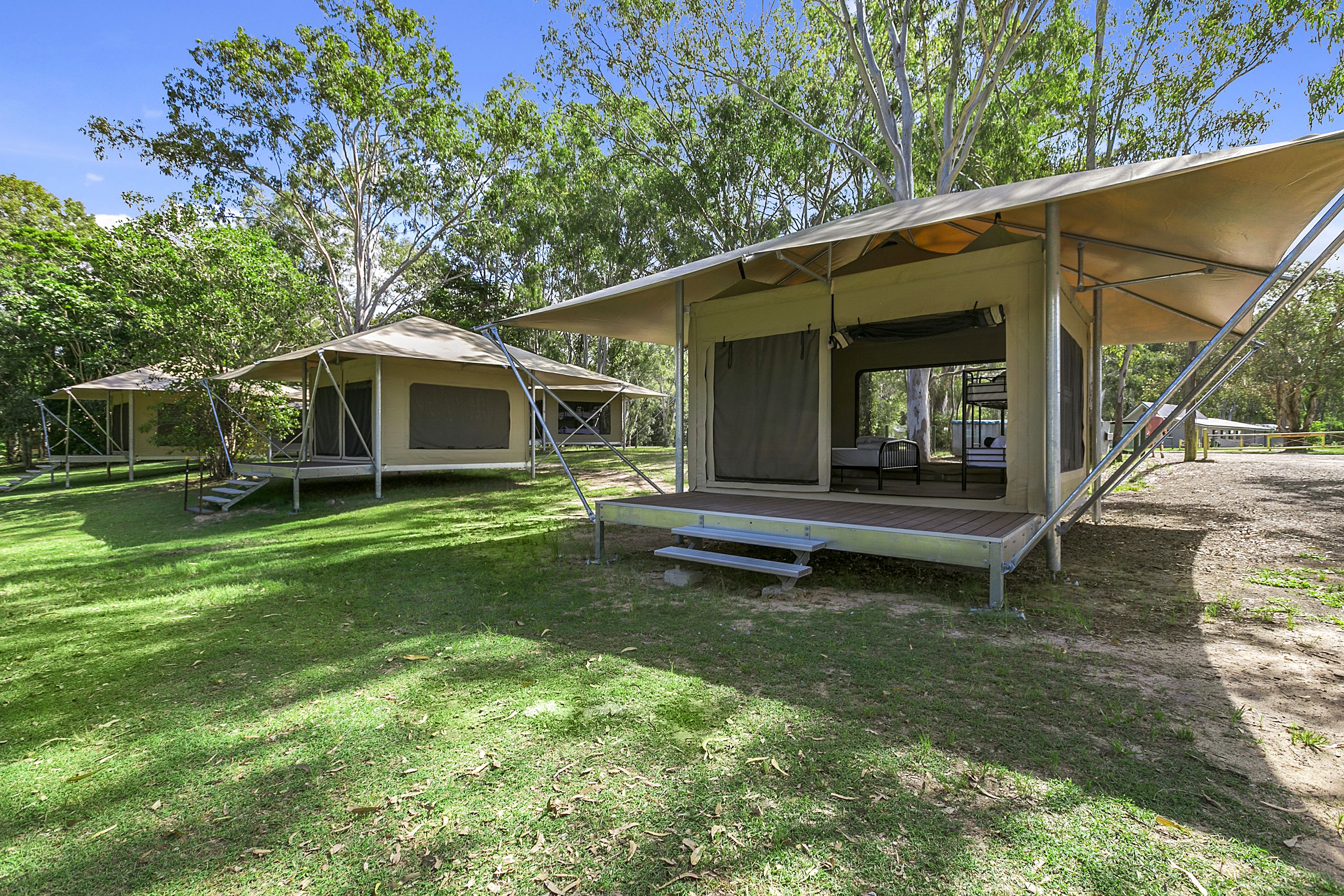 A campsite with two tents, each with a covered porch and steps leading up to the entrance.
