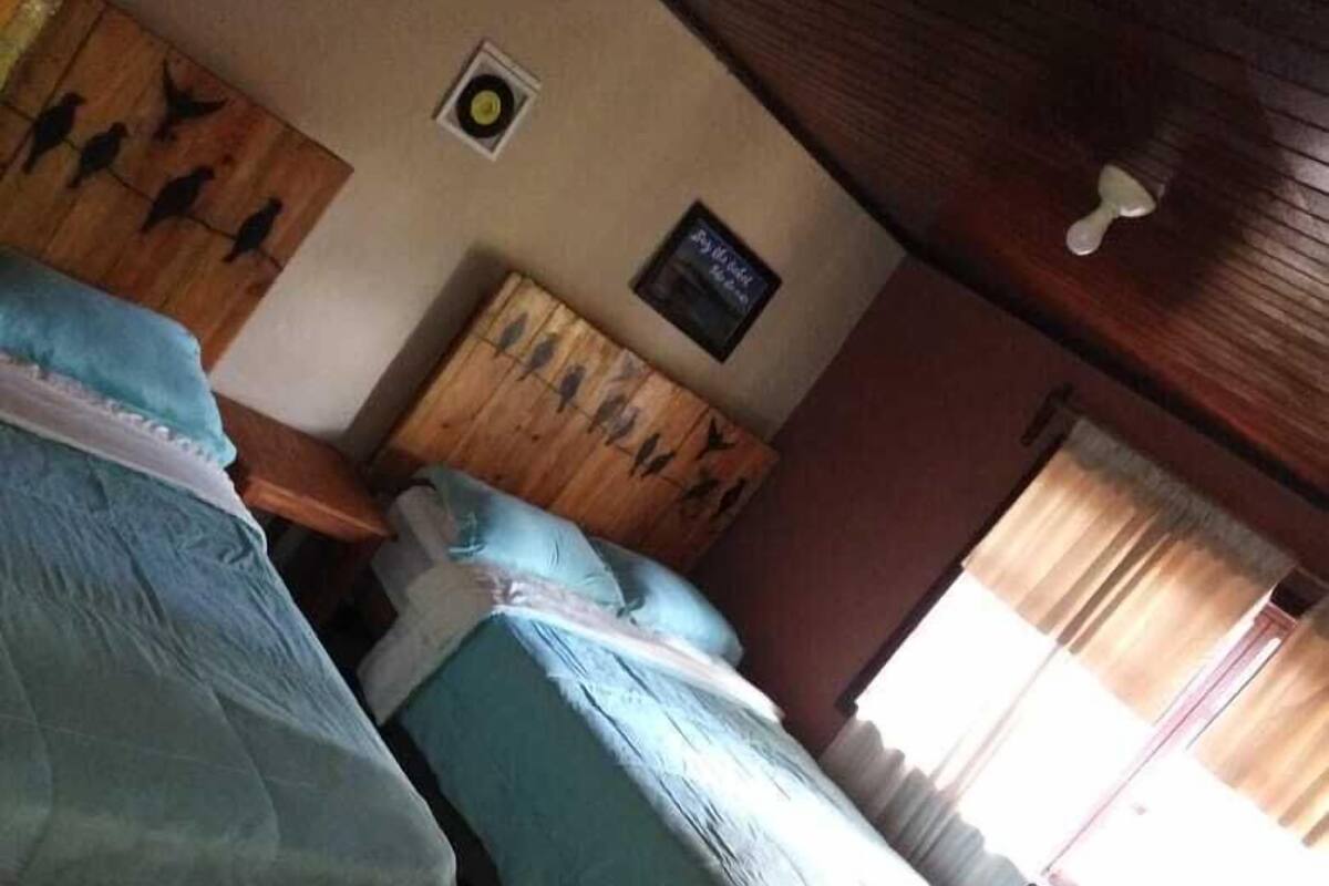A room with two beds, a wooden headboard, a small wall decoration, and a checkered floor.