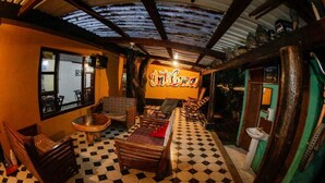 A room with a checkered floor, wooden furniture, a large window, and a sign that reads "IntiCasa". - Mitos Hostal (Intibucá)