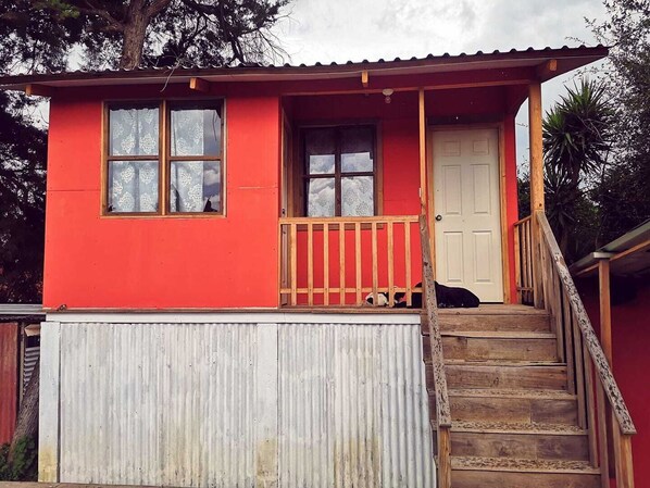 Un edificio rojo con una escalera de madera que conduce a una puerta.