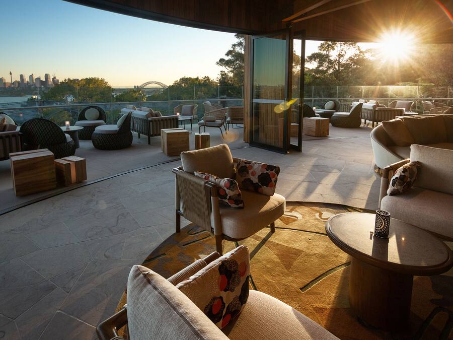 A rooftop terrace with outdoor seating, a glass door, and a city skyline view.