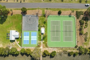 Ovenfra set et sportskompleks med basketballbane, tennisbaner og en bygning med mange vinduer.