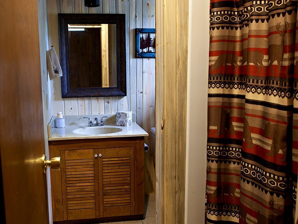 Une salle de bain avec des meubles de rangement en bois, un lavabo et un miroir.