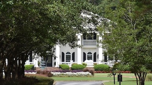 A white building with a symmetrical facade, arched windows, and a central entrance.