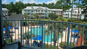 A hotel with a pool area, multiple balconies, and a view of the surrounding greenery.