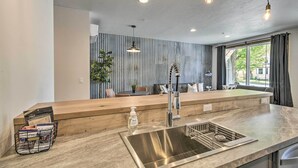 Een moderne keuken met een RVS-spoelbak, een houten aanrechtblad en hanglampen.