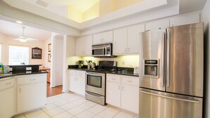 A modern kitchen with white cabinets, stainless steel appliances, and a black countertop. - Spacious Modern Pool Home, Family & Golf Trips - 4727 4 Bedroom Home by RedAwning (Inverness)