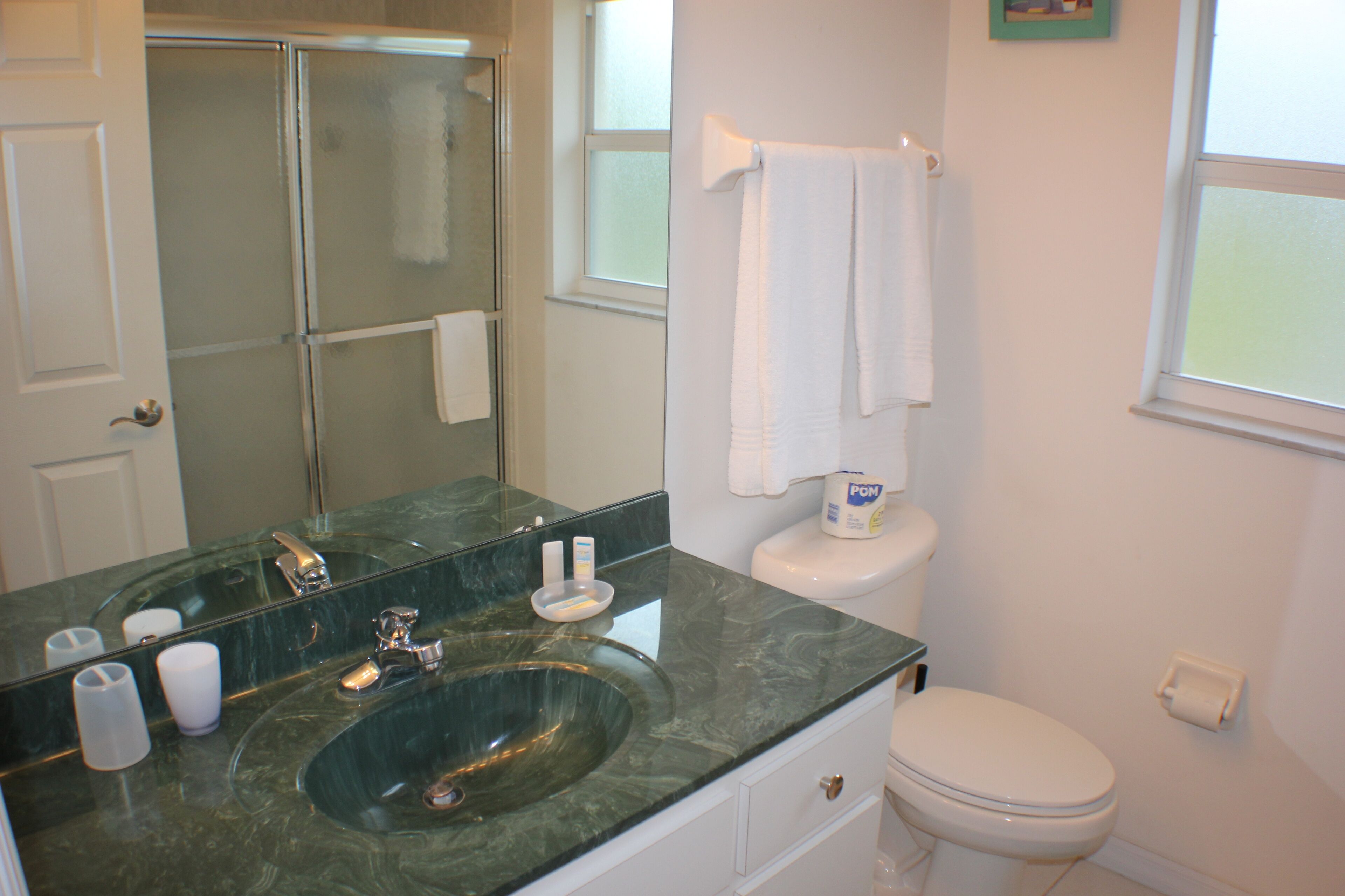A bathroom with a glass-enclosed shower, a white toilet, and a marble sink.