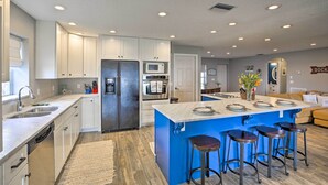 A modern kitchen with white cabinets, stainless steel appliances, and a blue island with bar stools. - Waterfront Lake Placid Home w/ Dock & Fire Pit (Lake Placid)