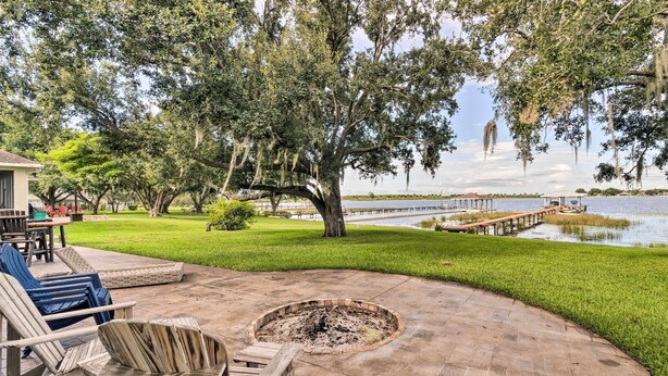 A patio area with a fire pit, outdoor furniture, and a view of a lake with a dock. - Waterfront Lake Placid Home w/ Dock & Fire Pit (Lake Placid)
