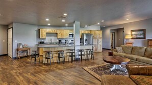 A spacious living area with a kitchen, wooden bar stools, a leather sofa, and a coffee table. - Black Hills Retreat ~ 3 Mi to ATV Trails! (Piedmont)