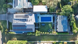 An aerial view of a residential property with a swimming pool, solar panels, and a well-maintained lawn. - Rocinante, Werri Beach - Gerringong (Werri Beach)