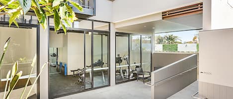 Un espacio interior moderno con paredes de vidrio, una escalera y equipo de ejercicio.