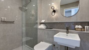 A modern bathroom with a glass-enclosed shower, a white sink, and a mirror above the sink.