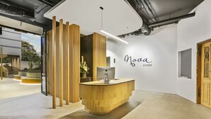 A reception area with a wooden reception desk, a wall-mounted sign reading "Nova KIAMA," and a modern interior design. - Nova Kiama (Kiama)