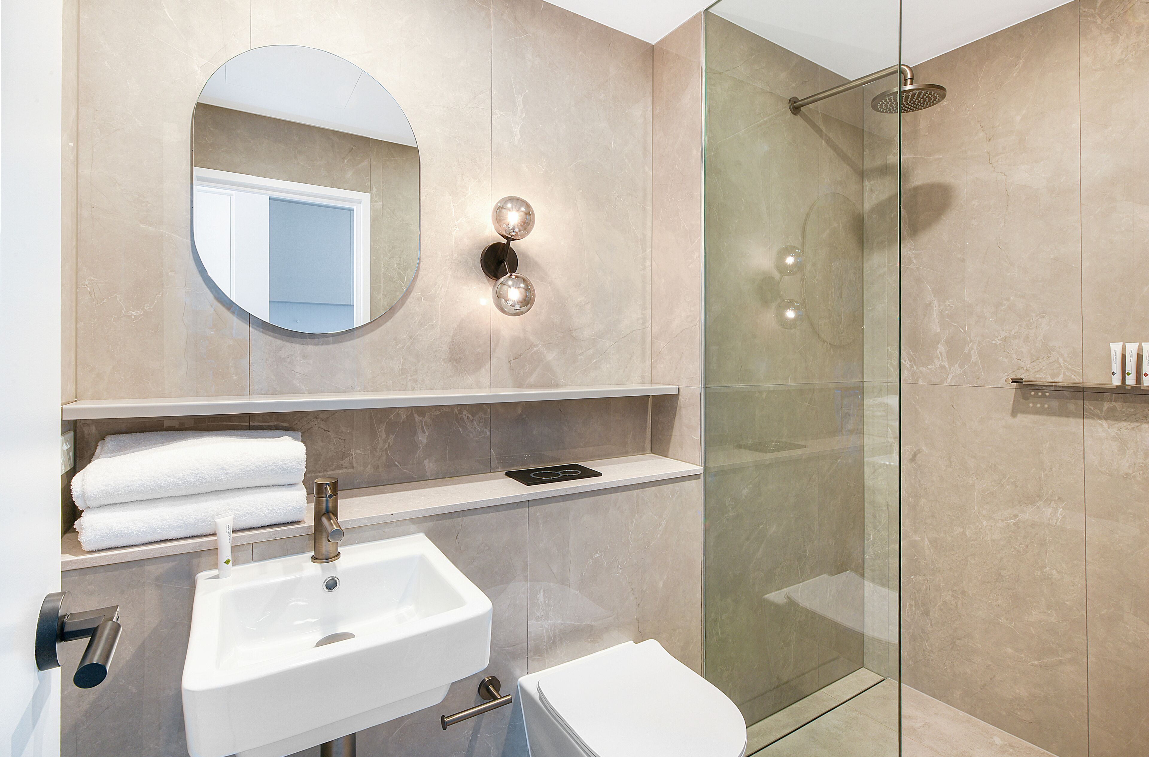 A modern bathroom with a sink, toilet, and glass-enclosed shower.
