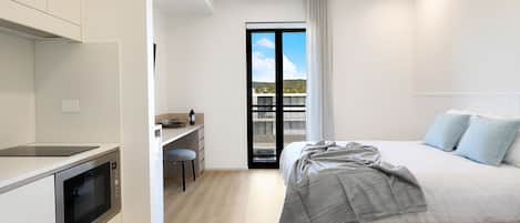 A modern bedroom with a bed, a desk, and a built-in oven.