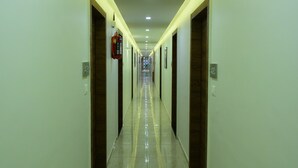 A long, well-lit hallway with doors on both sides, leading to individual rooms. - Hotel Royal Residency (Vadodara)
