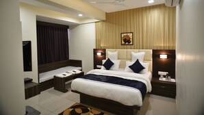 A modern hotel room with a large bed, bedside tables, a ceiling fan, and an air conditioning unit. - Hotel Royal Residency (Vadodara)