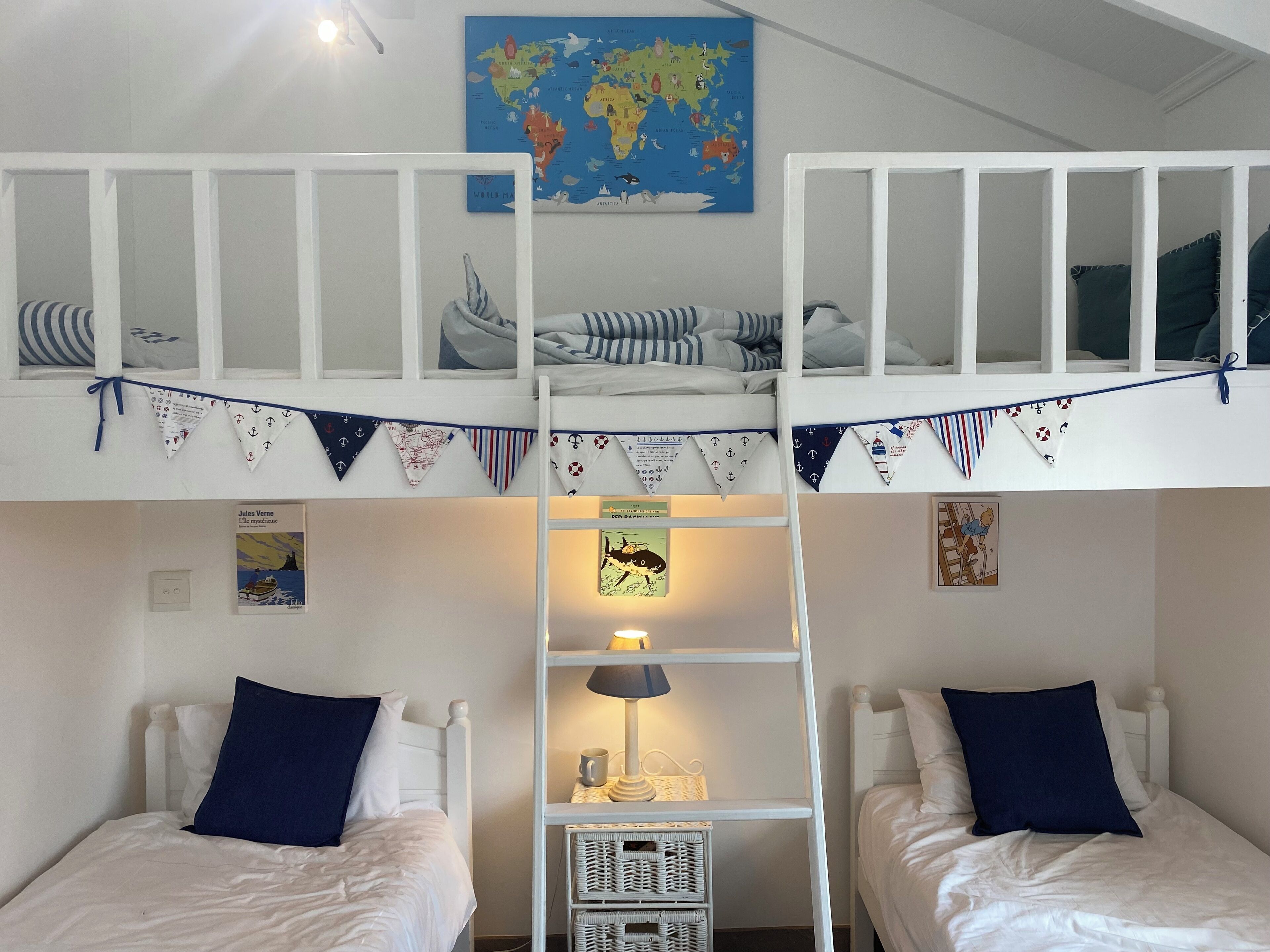 Een kamer met twee eenpersoonsbedden, een stapelbed, een wereldkaart en een lamp.