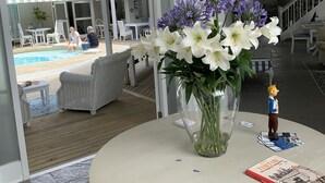 Ein Zimmer mit einem runden Tisch, einer Uhr, einer Blumenvase, einer kleinen Figur und einem Buch.