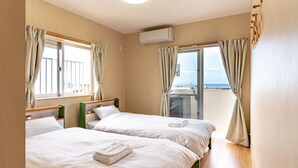 A hotel room with two beds, a balcony, and an air conditioning unit. - The Villas Machidoya (Motobu)
