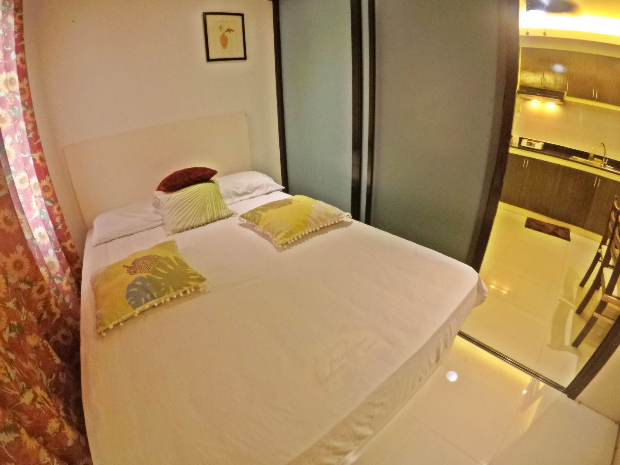 Een hotelkamer met een bed, nachtkastje, spiegel en raam.