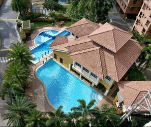 Un hôtel doté d’une piscine, de plusieurs balcons et d’un jardin tropical.