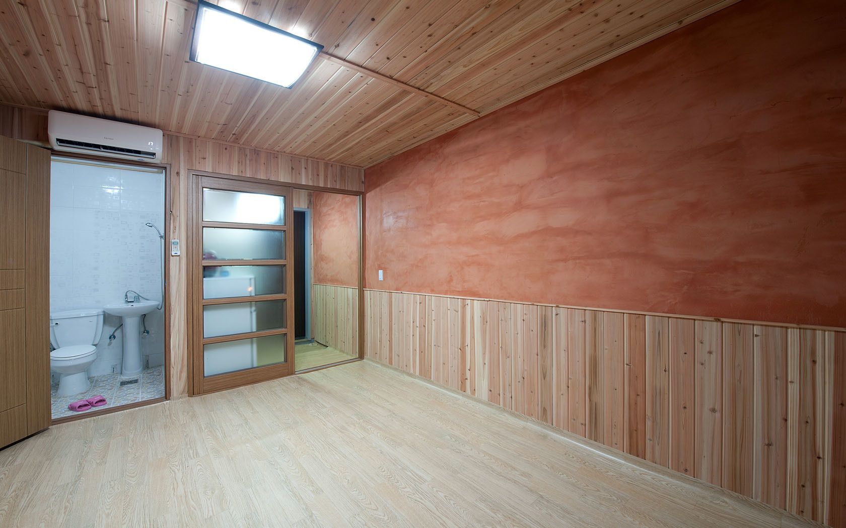A room with a wooden ceiling, a built-in wardrobe, a toilet, and a sink.